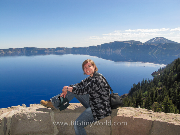 Brianna sitting on an overlook to Crater Lake | BIGtinyWorld Travel