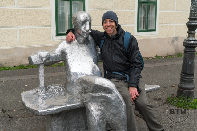 Aaron posing with a metal statue sitting on a bench in Zagreb, Croatia
