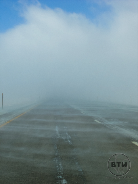 A low cloud obscuring the highway in Idaho as snow blows across the road