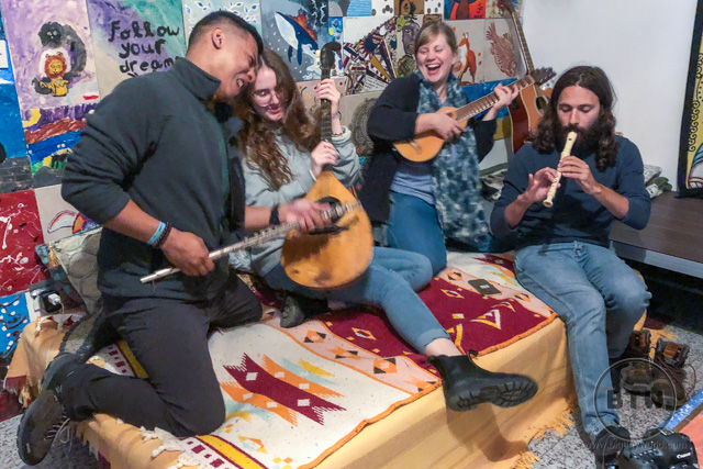 A group of people jokingly playing instruments in a hostel in Omis, Croatia